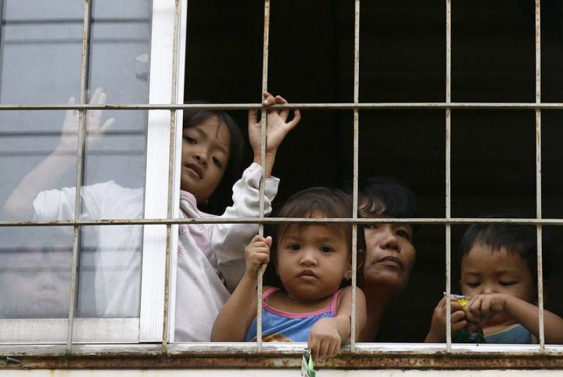 Una familia mira desde la ventana de un colegio convertido en refugio en un suburbio de Manila