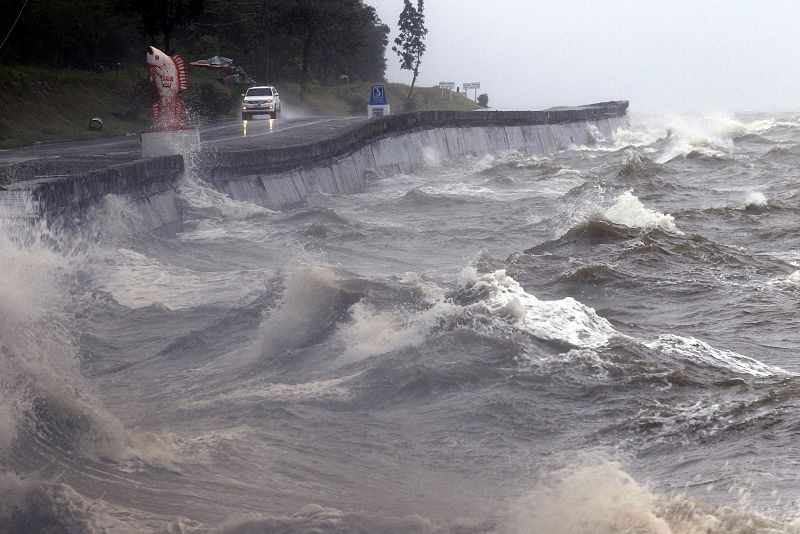 Un vehículo circula por una carretera destrozada junto a la costa en la ciudad de Atimonan