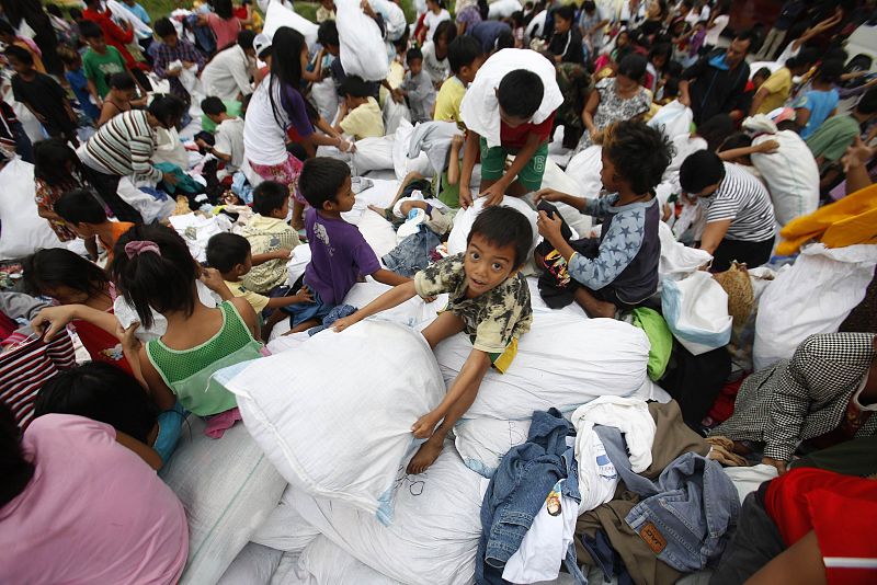 Un niño recoge un saco con ropa donada en un centro de evacuación en Manila