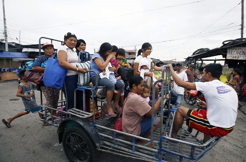 Varios filipinos se dirigen hacia el centro de evacuación provisional de un suburbio de Manila.