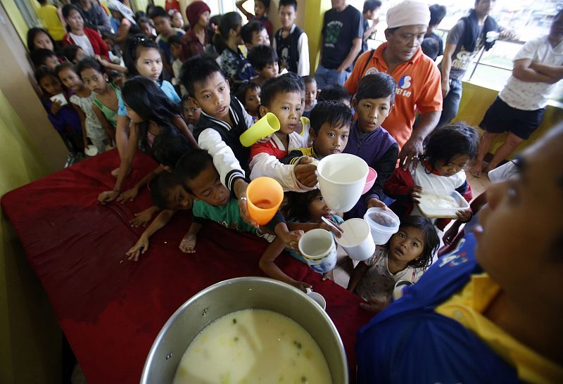Un grupo de niños hace cola para recibir comida en un centro de evacuación cerca de Manila