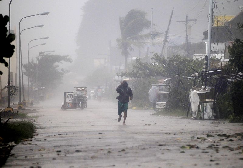 Un hombre corre por una calle de Atimonan bajo una fuerte lluvia