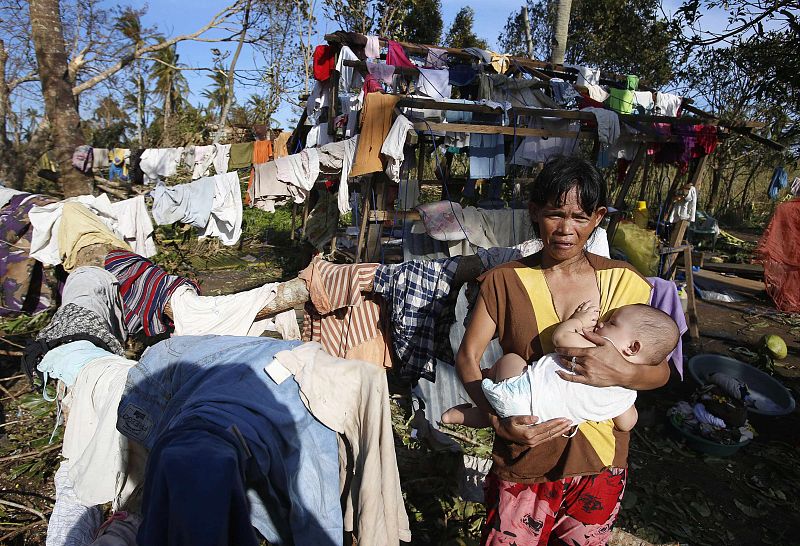 Una mujer amamante a su bebé ante lo que ha quedado de su casa en Dolores, en la isla de Samar