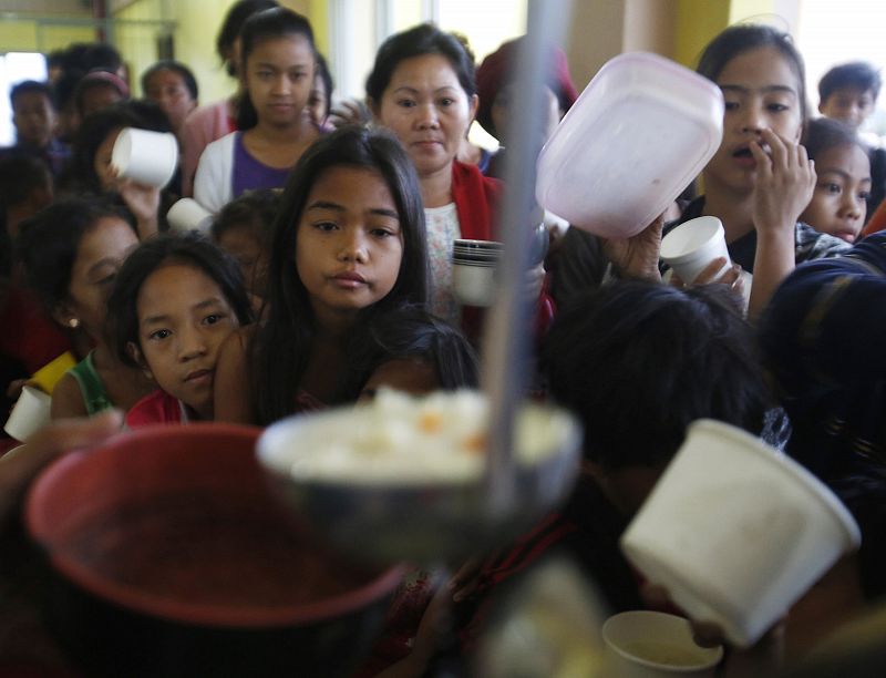 Unos niños esperan para recibir su ración de comida en un centro de evacuación cerca de Manila