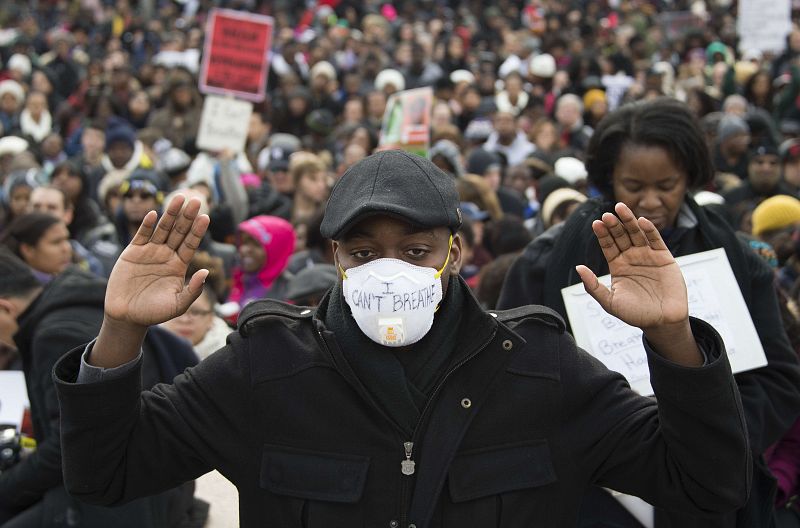 Un manifestante levanta las manos y porta una mascarilla donde se ve escrito "No puedo respirar", las últimas palabras de Eric Garner antes de morir.