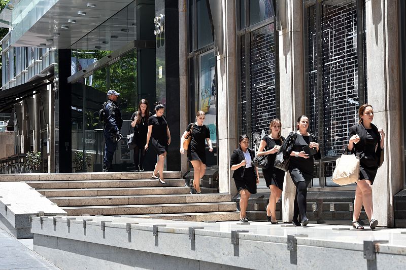 Un grupo de oficinistas son evacuadas de un edificio cercano a la cafetería escenario de un secuestro en Sídney