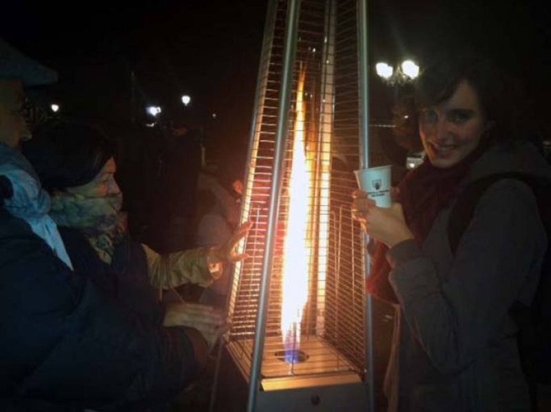 Asistentes al sorteo de la lotería 2014 intentan entrar en calor en el exterior del Teatro Real de Madrid.