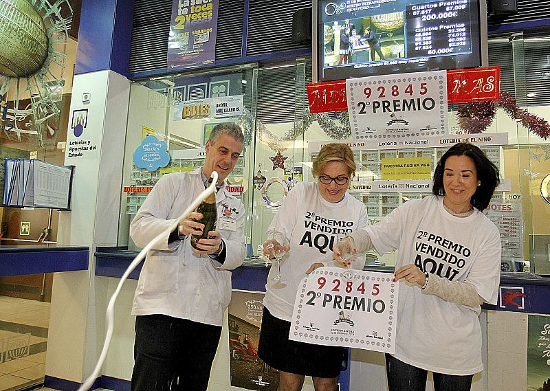 Trabajadores de la administración de lotería número 82 de Zaragoza, situada en un centro comercial, celebran el reparto del segundo premio de la Lotería de Navidad, el 92.845.