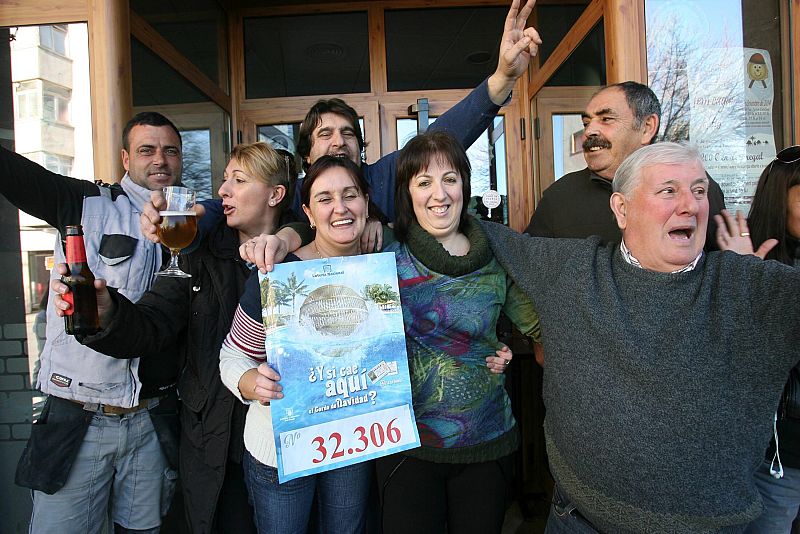 La propietaria del Bar Gil de El Vendrell (Tarragona) celebra junto a algunos de los agraciados y otros clientes el haber repartido parte de uno de los quintos premios, el 32.306, vendido en Sitges.