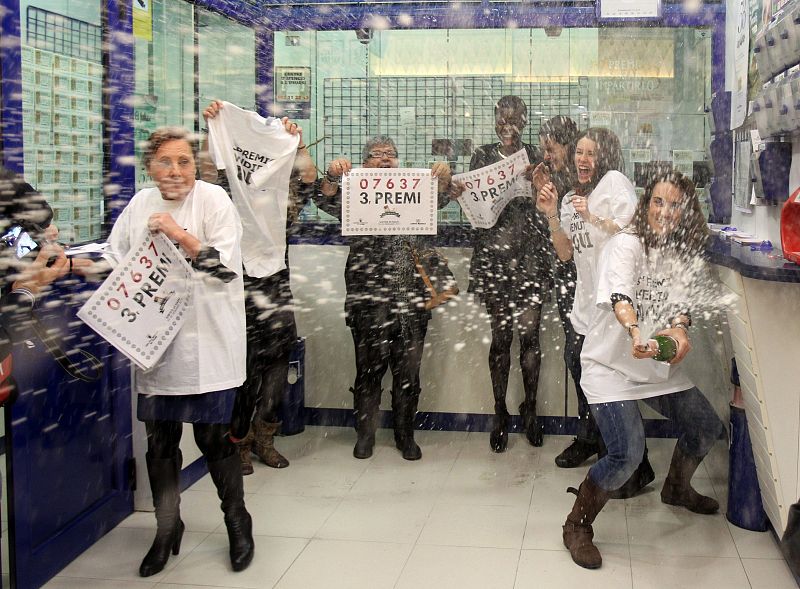 La lotera de la administración número 37 de L'Hospitalet (Barcelona) ubicada en un centro comercial, celebra junto a unos de los agraciados el haber vendido íntegramente el tercer premio de la lotería de Navidad.