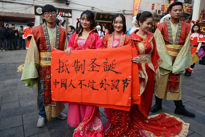 Changsha, provincia de Hunan, China: estudiantes ataviados con trajes tradicionales sostienen un cartel en el que se lee: "Resiste la Navidad, los chinos no deberían celebrar fiestas extranjeras"