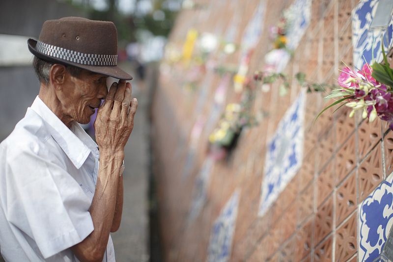 Somjit Bhuddharaj, de 58 años, reza frente a la placa que recuerda a su familia, muerta en el tsunami