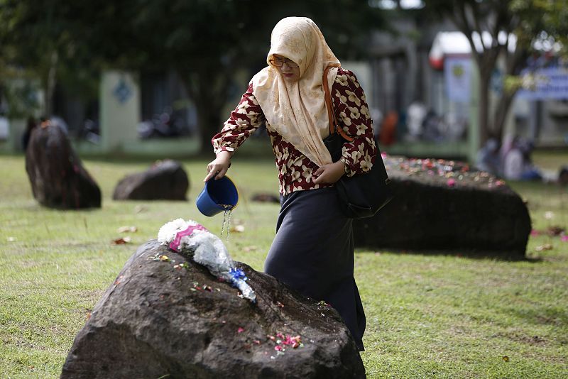 Una mujer vierte agua sobre una piedra que marca la fosa común de las víctimas del tsunami en Banda Aceh, la 'zona cero' del desastre