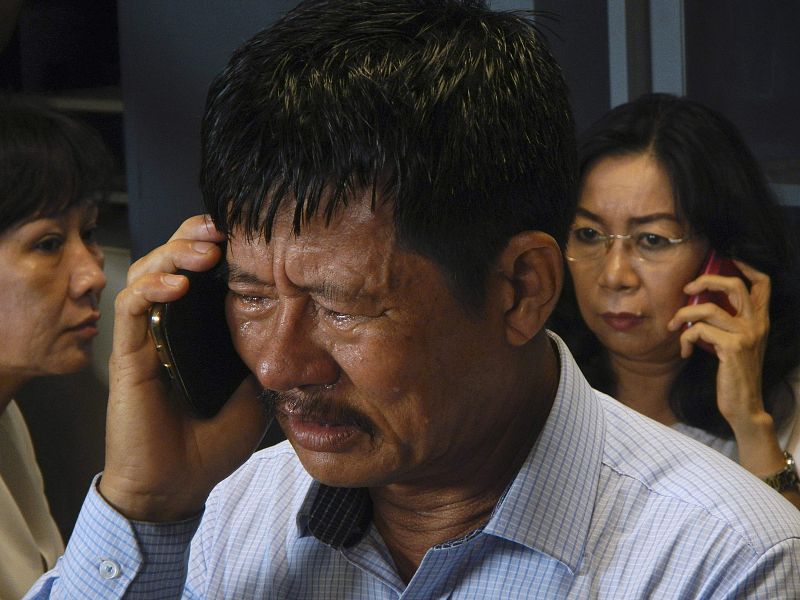 Los familiares de los desaparecidos hablan por teléfono mientras esperan noticias del avión AirAsia desaparecido.