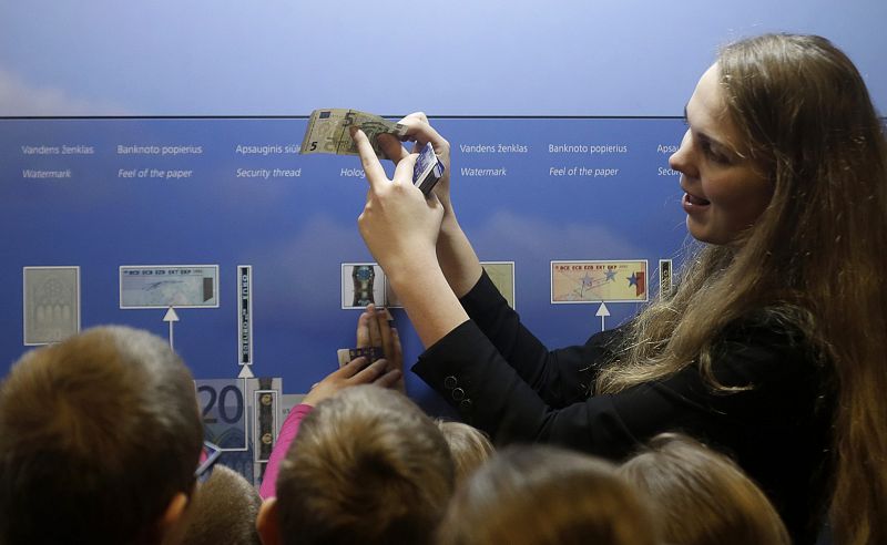 Una guía muestra las medidas de seguridad de un billete de cinco euros en Vilna