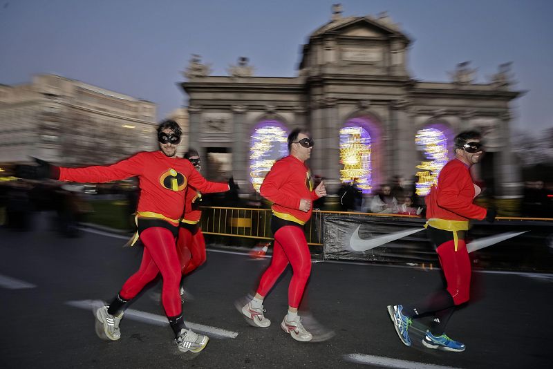 Varias personas disfrazadas a su paso por la Puerta de Alcalá.