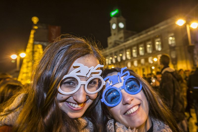 Dos asistentes a las campanadas de la Puerta del Sol lucen unas gafas con el número del nuevo año, 2015.