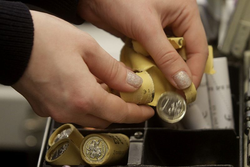 Un cajero coloca monedas de un euro en su caja en una tienda en Vilna