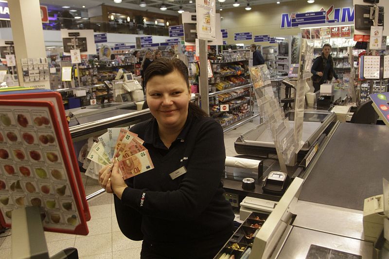 Una cajera muestra billetes de 5, 10 y 20 euros en una tienda en Vilna