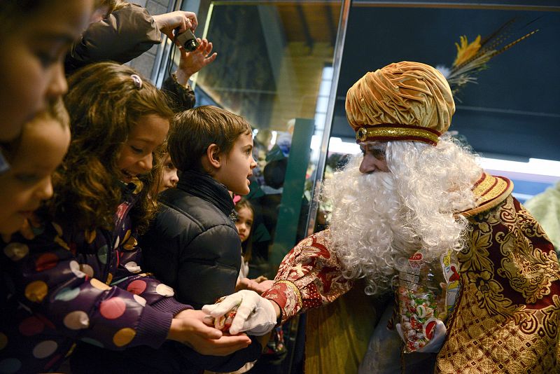 El rey Melchor saluda a un grupo de niños a su llegada a la estación de tren de Ourense