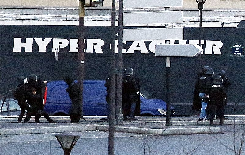 Los agentes atienden a un compañero tendido en el suelo tras el asalto a la tienda al este de París.