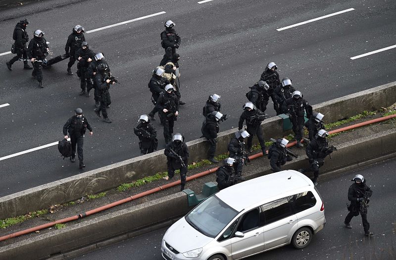 Agentes franceses cruzan la carretera de circunvalación para tomar posiciones previas al asalto del supermercado en Porte de Vincennes.