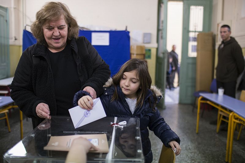 Una mujer con un niño deposita su voto en un colegio electoral de Atenas, durante las elecciones parlamentarias de Grecia.