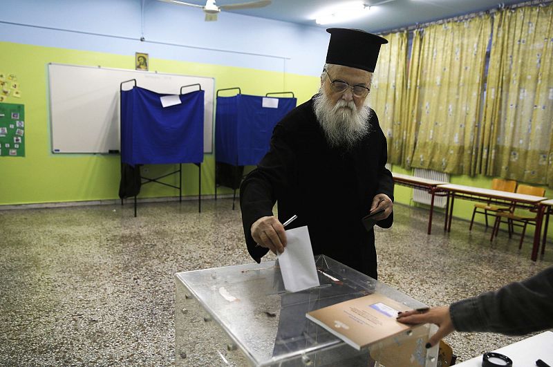 Un sacerdote ortodoxo griego deposita su voto en un colegio electoral de Atenas (Grecia).