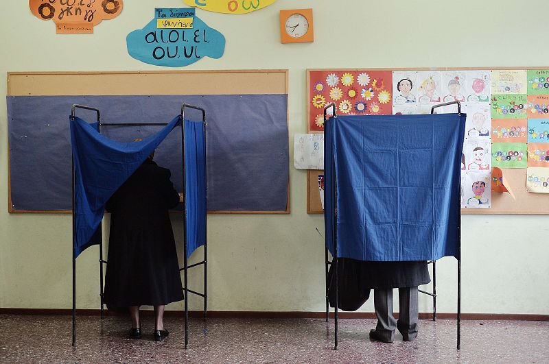 Dos personas preparan sus votos en una cabina de votación en un colegio electoral en Atenas (Grecia).