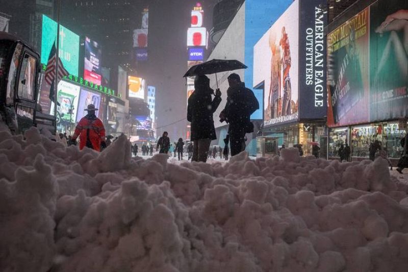 Dos viandantes se refugian de la nieve bajo un paraguas en Times Square, Nueva York. 