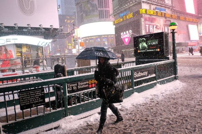 Una mujer se dirige a una estación del metro en medio de la nevada en Nueva York.