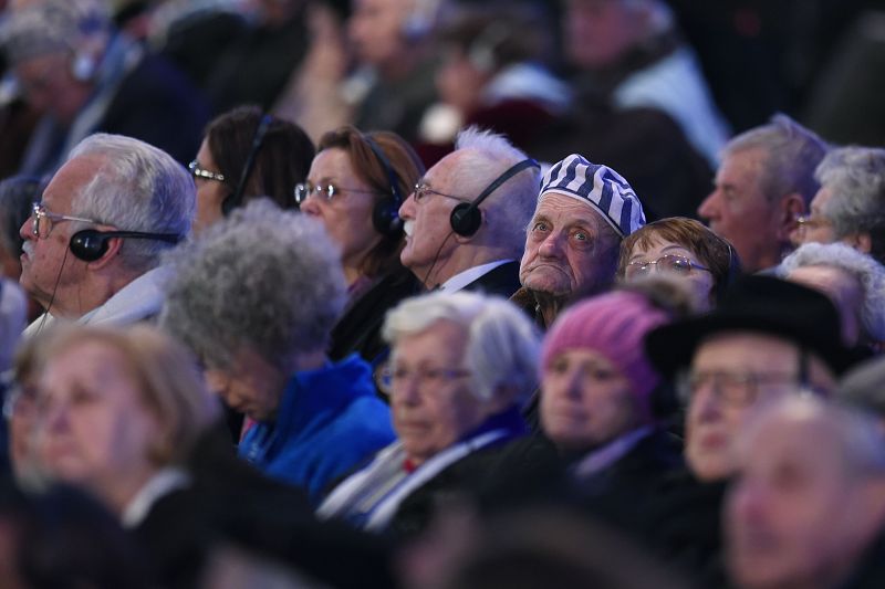 Uno de los supervivientes del Holocausto viste el gorro de prisionero en medio de otros compañeros.