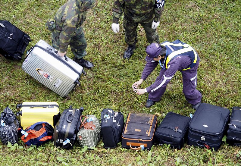 Un policía toma fotografías de las maletas de los pasajeros del avión siniestrado