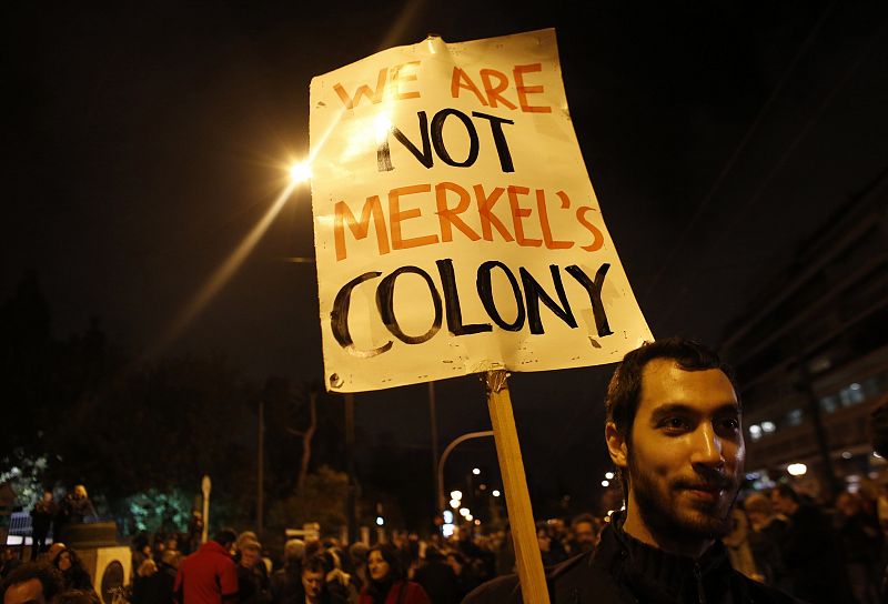 Un manifestante sostiene una pancarta en la que se lee en inglés: "no somos la colonia de Merkel"