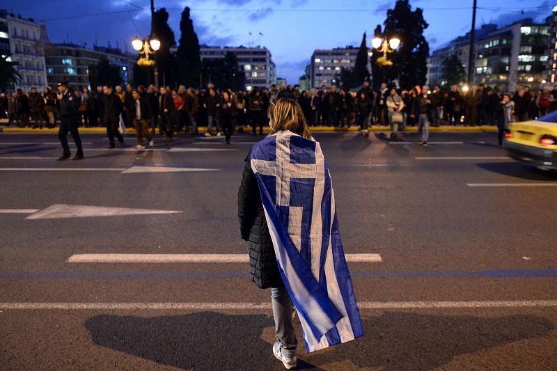 Una mujer con la bandera de Grecia a modo de capa en Atenas