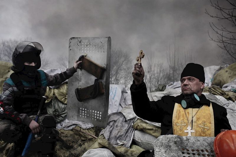 Un sacerdote ortodoxo mientras bendice a los manifestantes apostados tras una barricada en Kiev. Segundo premio World Press Photo 2014 en la categoría de Noticias de Actualidad.