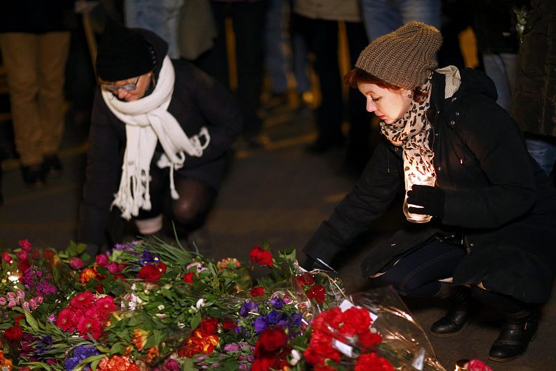 Dos mujeres colocan flores como señal de solidaridad con las víctimas