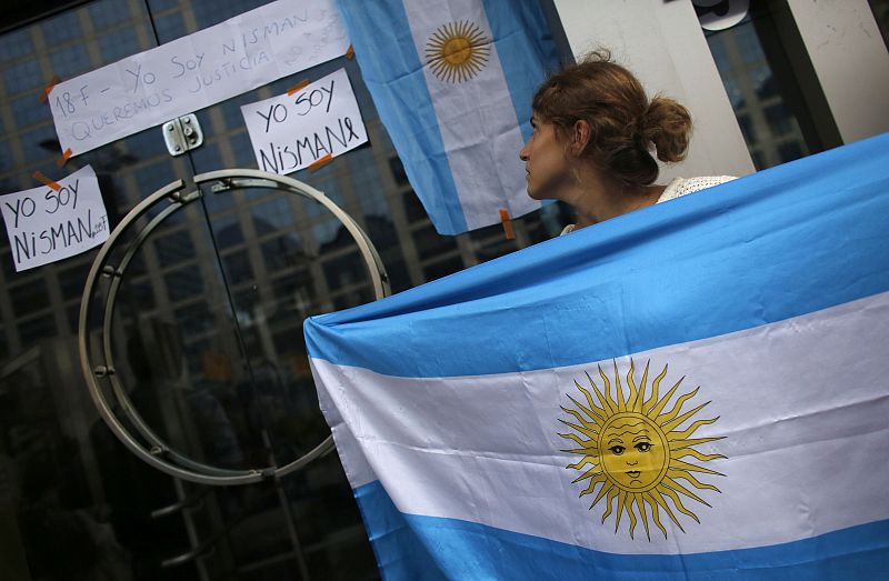 Una argentina que ha viajado desde Brasil mira los carteles durante la protesta mientras muestra una bandera de la República Argentina.