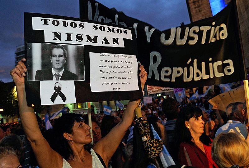 Una mujer levanta una pancarta con el mensaje "Todos somos Nisman" junto a la foto del fiscal fallecido en la manifestación en su memoria.