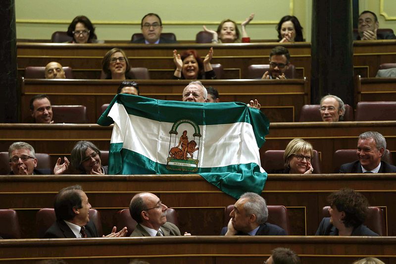 El diputado socialista Manuel Pezzi muestra una bandera de Andalucía en defensa de las políticas de la Junta