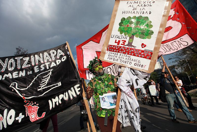 Un mexicano sostiene carteles durante la manifestación para recordar a los 43 jóvenes