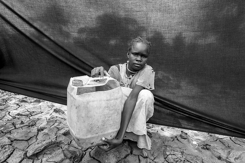 María, de 10 años, junto con un bidón en el campamento de Jamam (Sudán del Sur).