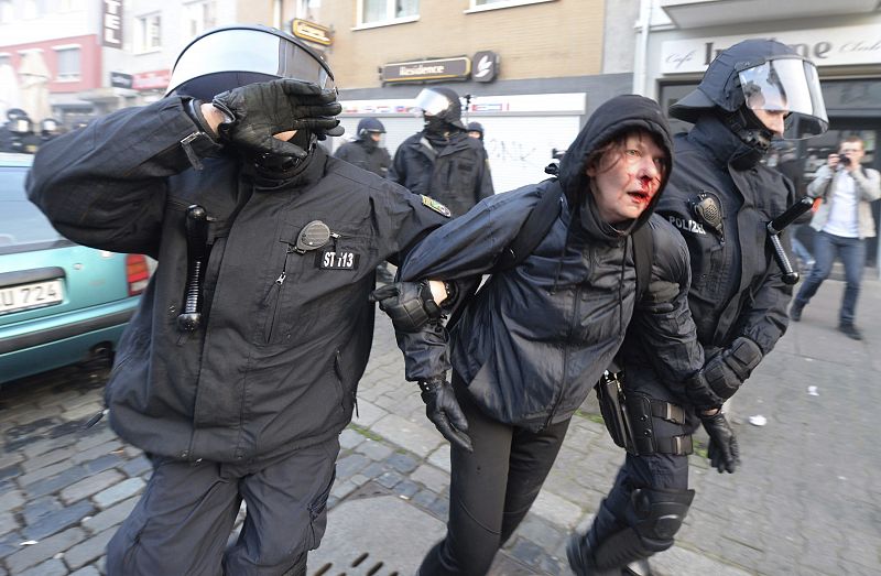 Policías antidisturbios escoltan a una manifestante herida durante la protesta