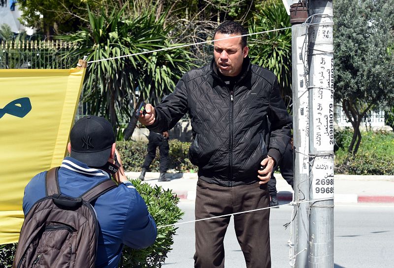 Un policía tunecino armado trata de expulsar de los alrededores del lugar del asalto a un fotógrafo