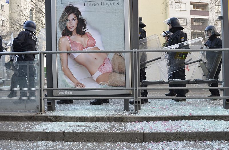 Policías antidisturbios se preparan junto a una marquesina de autobús hecha añicos