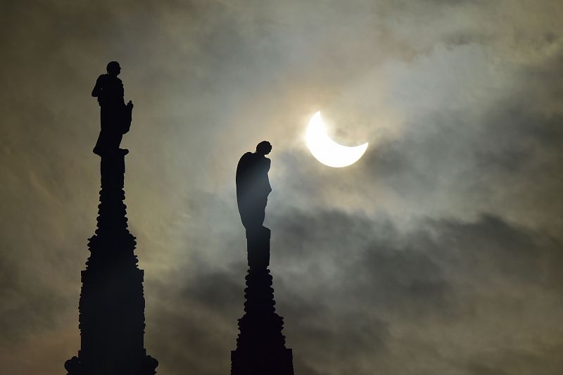 Así se ha visto el eclipse junto a las estatuas de la catedral de Milán, en Italia.