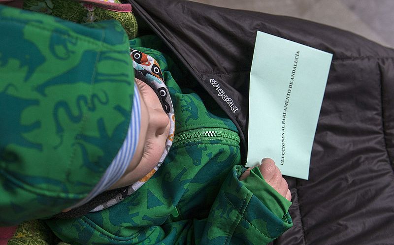 Un niño lleva la papeleta para las votaciones, en un colegio electoral de Jaén, durante la jornada de elecciones autonómicas en Andalucía.