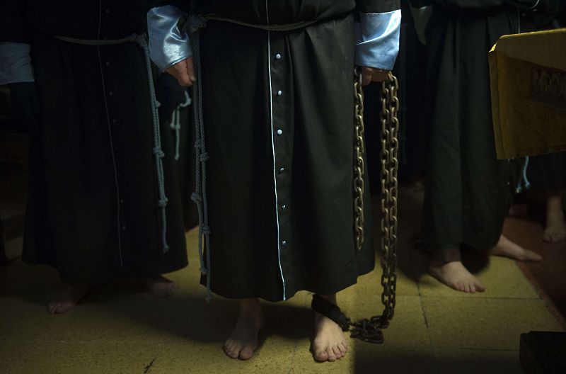 Penitentes encadenados esperan el comienzo de la procesión de Jesús Flagelado en Santiago de Compostela