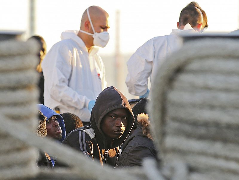 Migrants wait before disembarking from a Coast Guard boat in the Sicilian harbour of Augusta