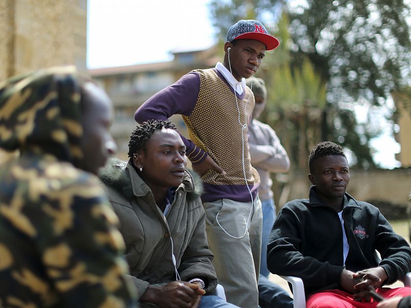 Adolescent migrants Mustafa (2nd R) from Gambia and Ishmael (R) from Sierra Leone stand in a courtyard at an immigration centre in Caltagirone, Sicily